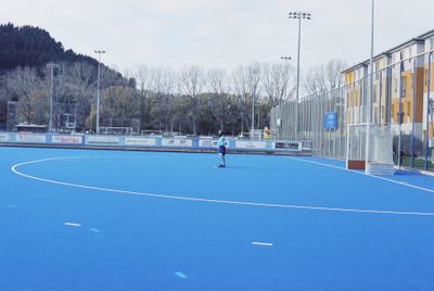 Hockey goal keeper alone on blue pitch